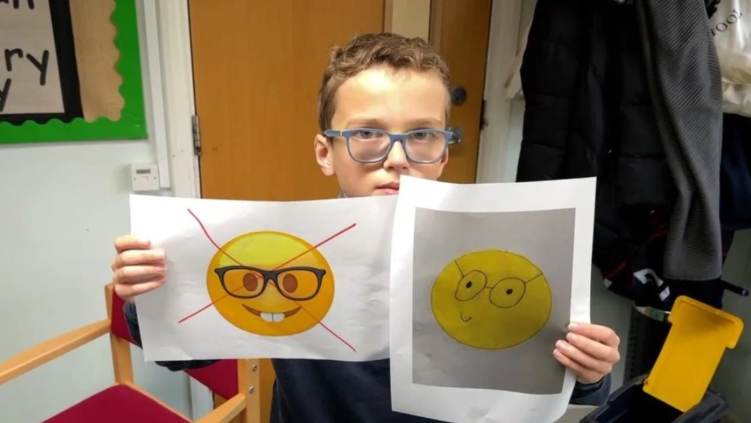 Teddy holds up the current offensive nerd face emoji with his own replacement genius emoji on the right.  Image credit BBC – Teddy, 10, launches petition to get Apple to change offensive emoji